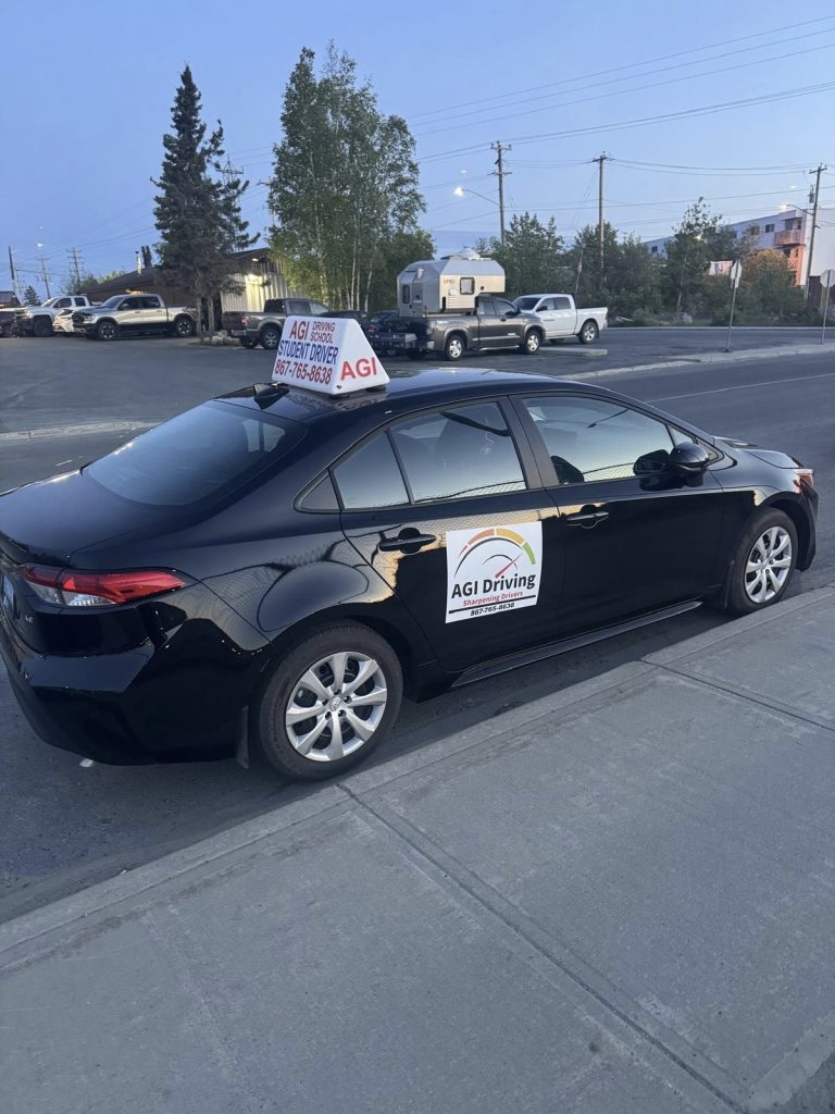 agi-driving-student-driver-black-car-on-street-with-signage